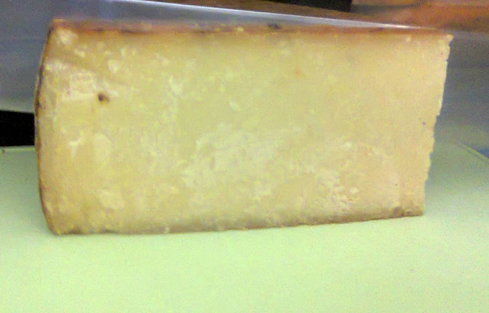 Spicchio di Bagòss stagionato con pasta gialla compatta e crosta scura