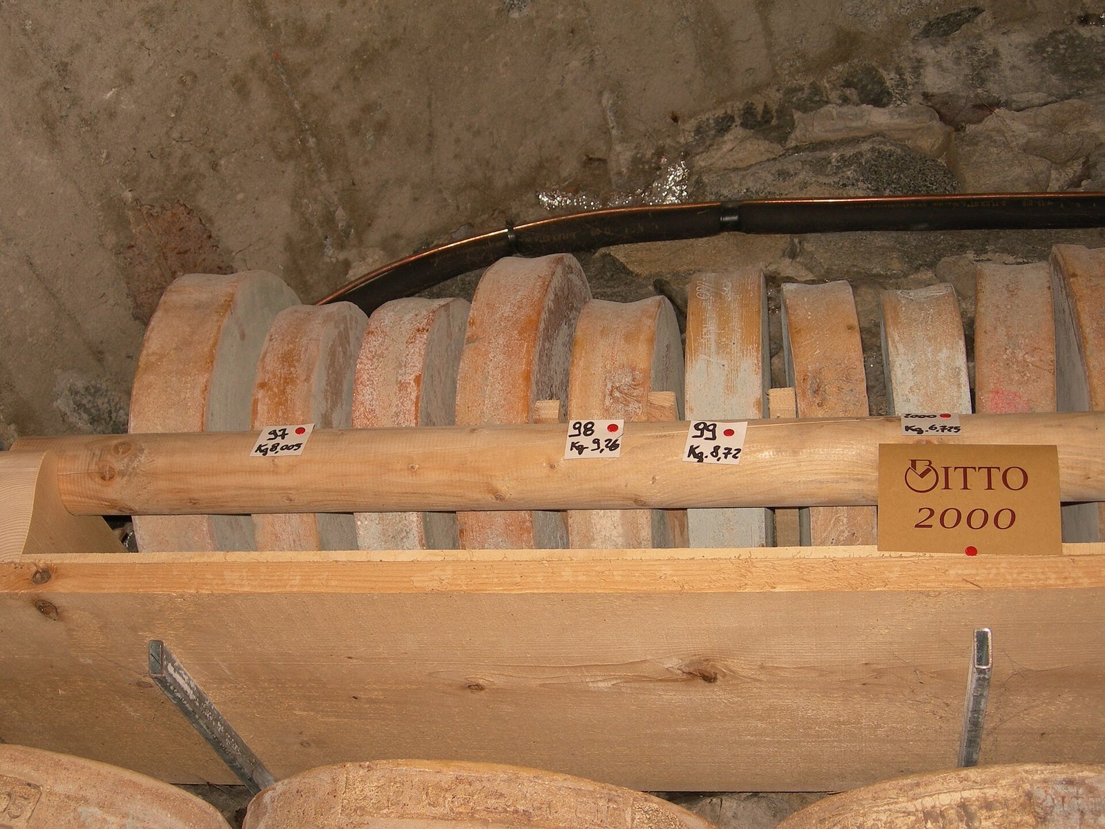 Forme di Bitto in stagionatura su assi di legno
