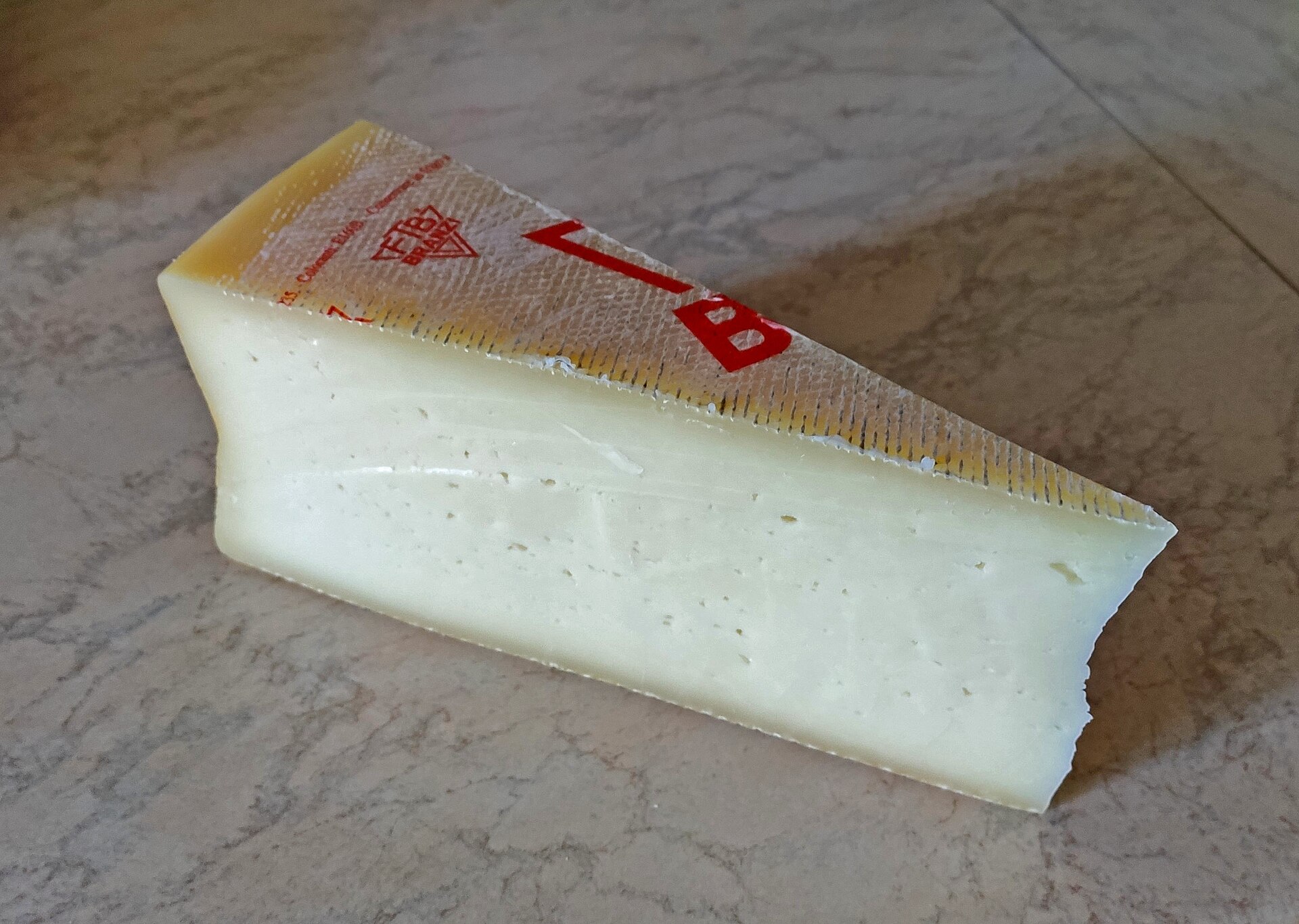 Fetta di formaggio Branzi con crosta e occhiatura tipica