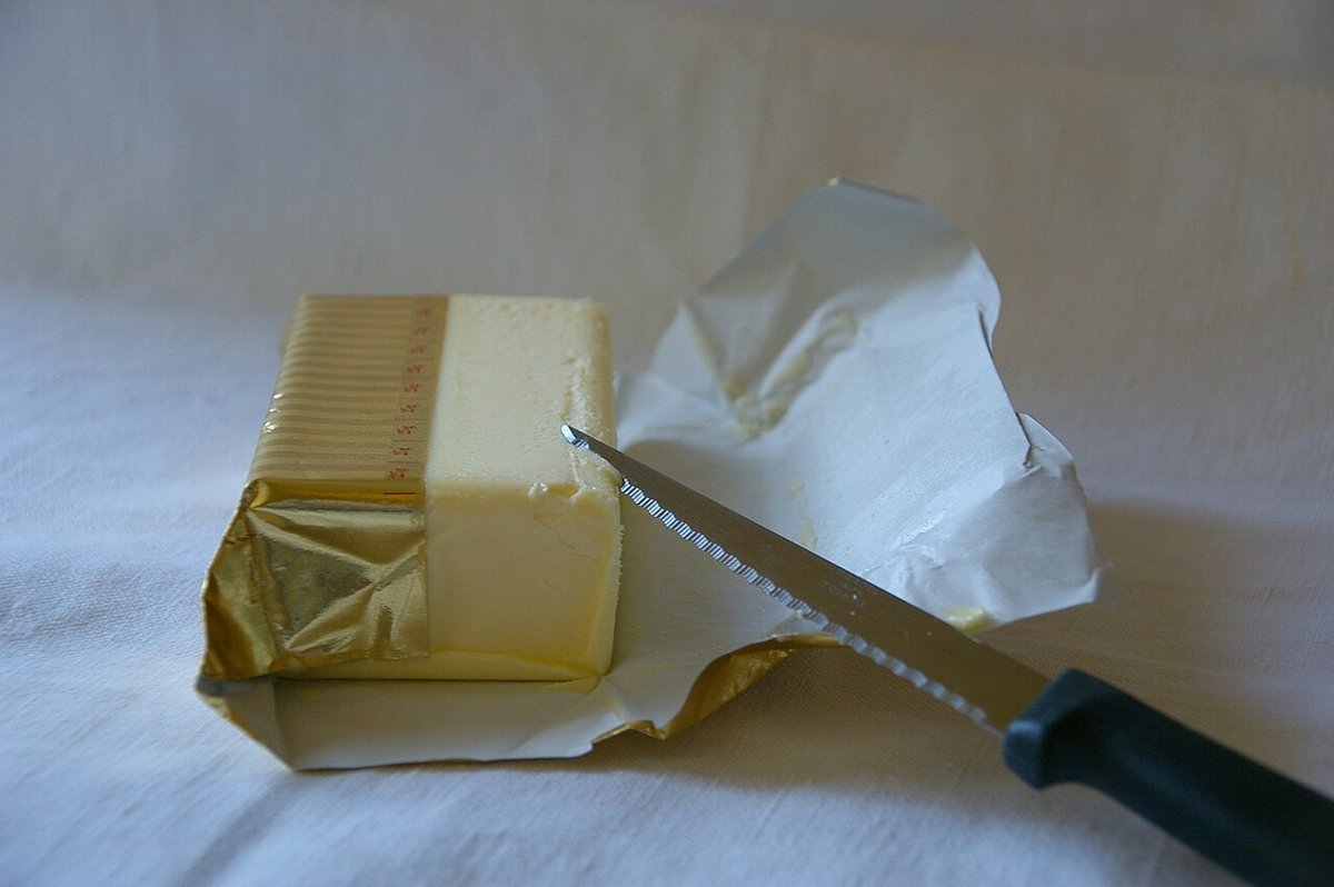 Panetto di burro su carta, con un coltello