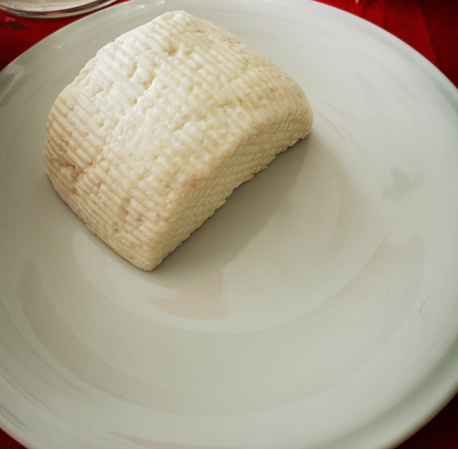 Una piccola forma di cacioricotta pugliese su un piatto bianco