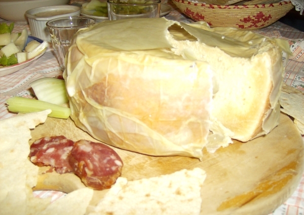 Forma di casu marzu aperta su un tagliere, servita con salsiccia e pane carasau