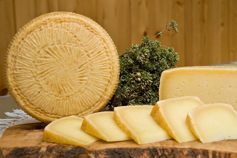 Forma intera di Pecorino di Filiano con i segni della fuscella e spicchi su un tagliere