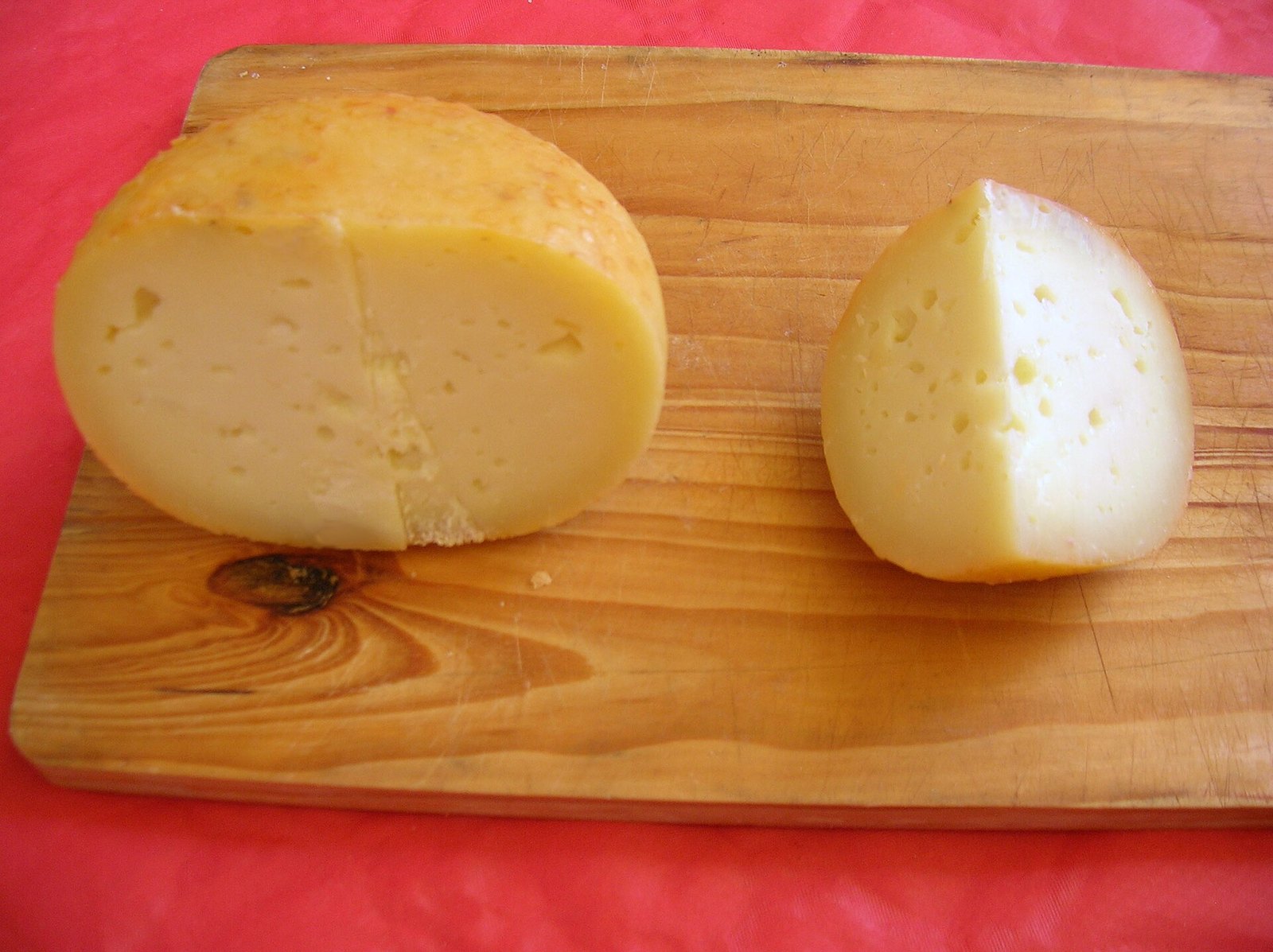 Forma intera e mezza forma di Pecorino di Pienza con pasta paglierina su tagliere di legno
