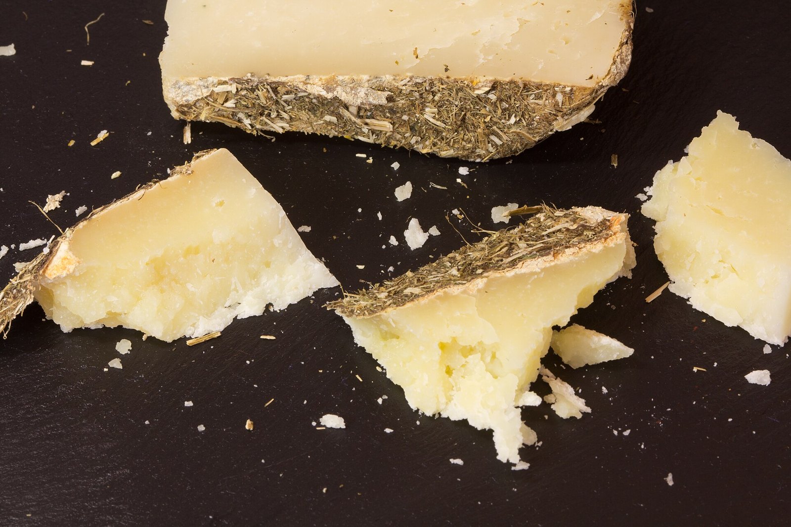 Pezzi di pecorino stagionato in grotta con crosta scura e pasta paglierina friabile