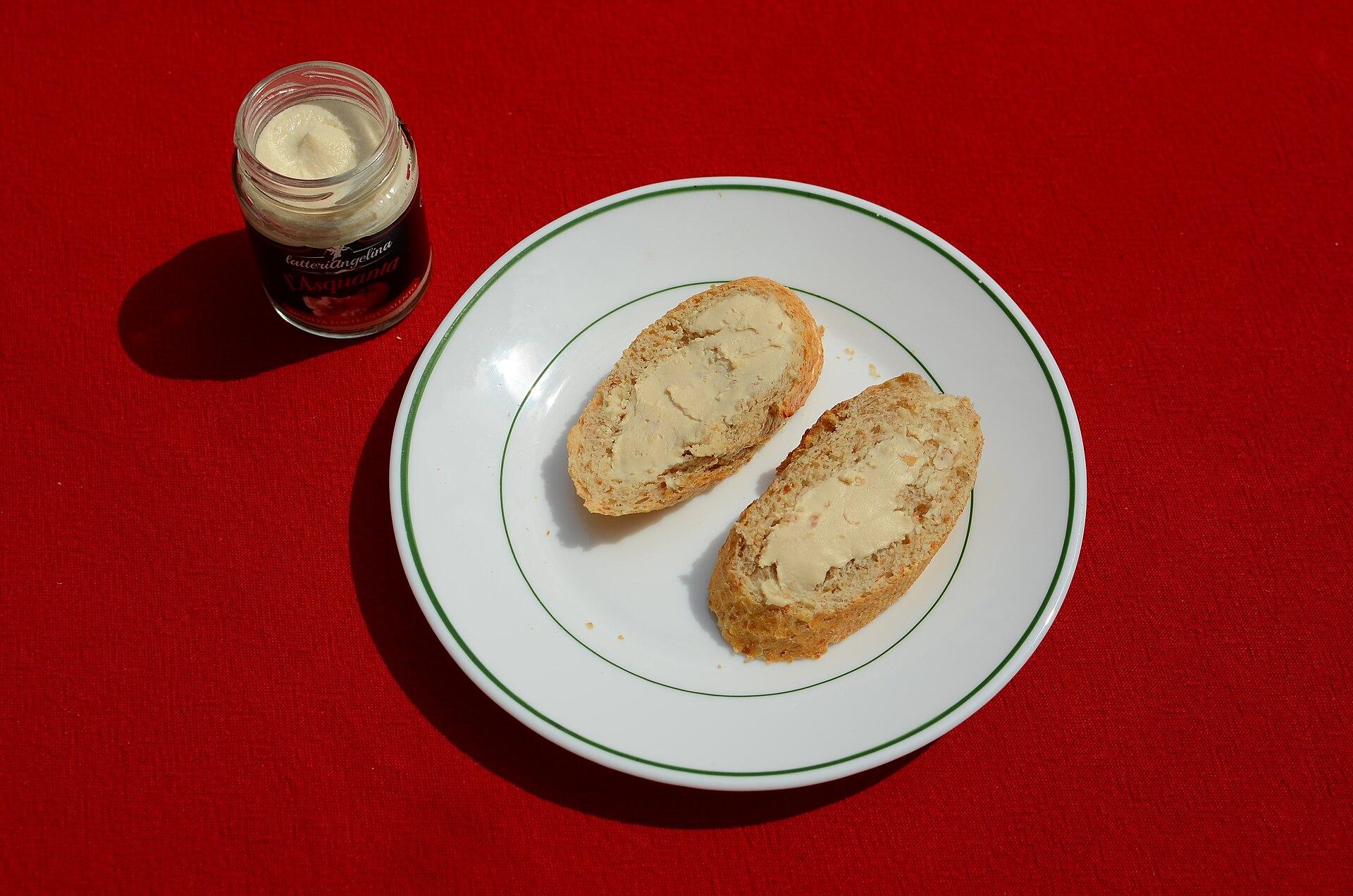 Un vasetto di ricotta forte con fette di pane spalmate