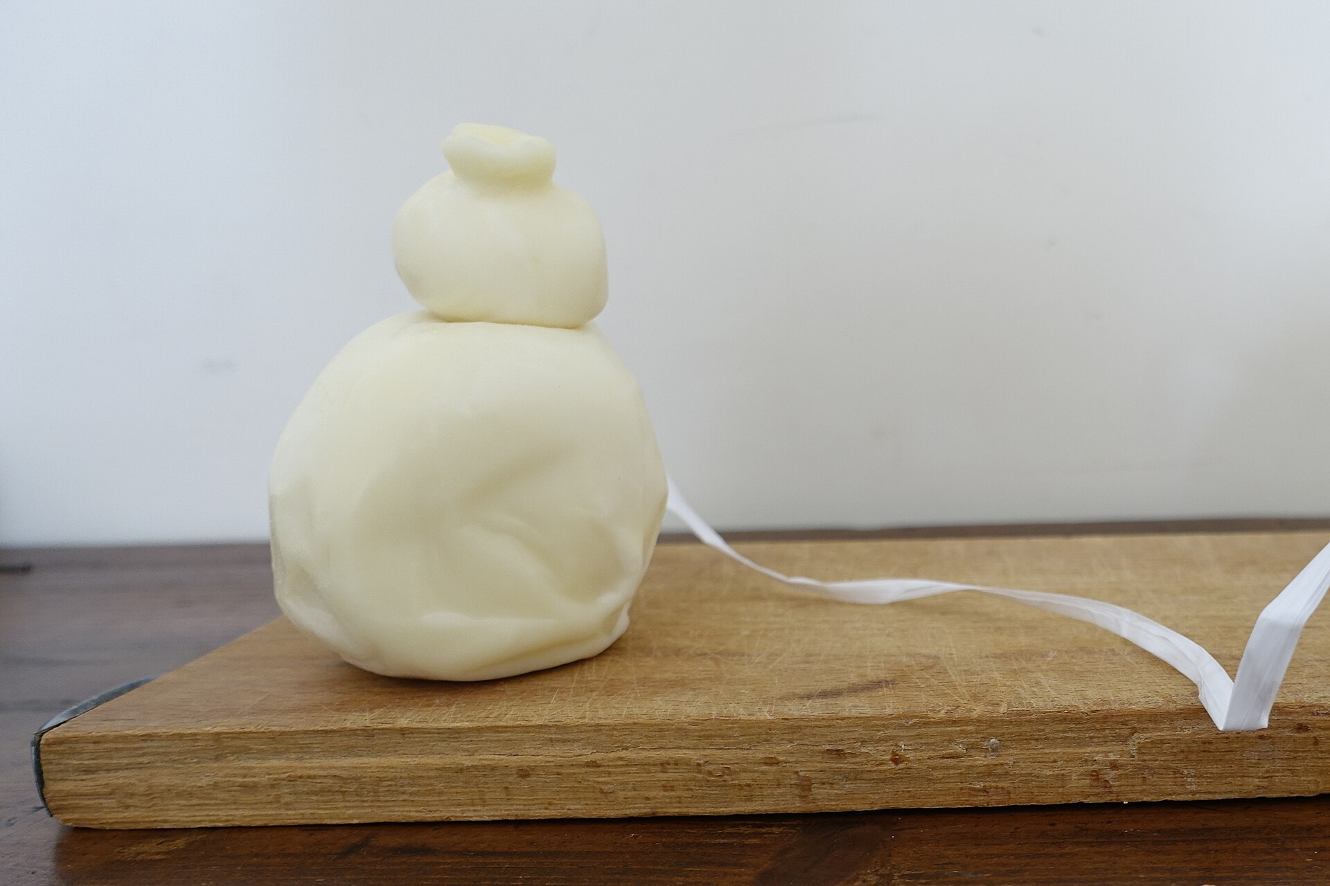 Una scamorza bianca a forma di pera su un tagliere