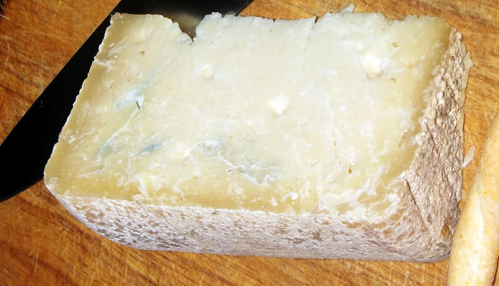 Fetta di Toma del lait brusc con pasta bianca gessosa e venature blu naturali