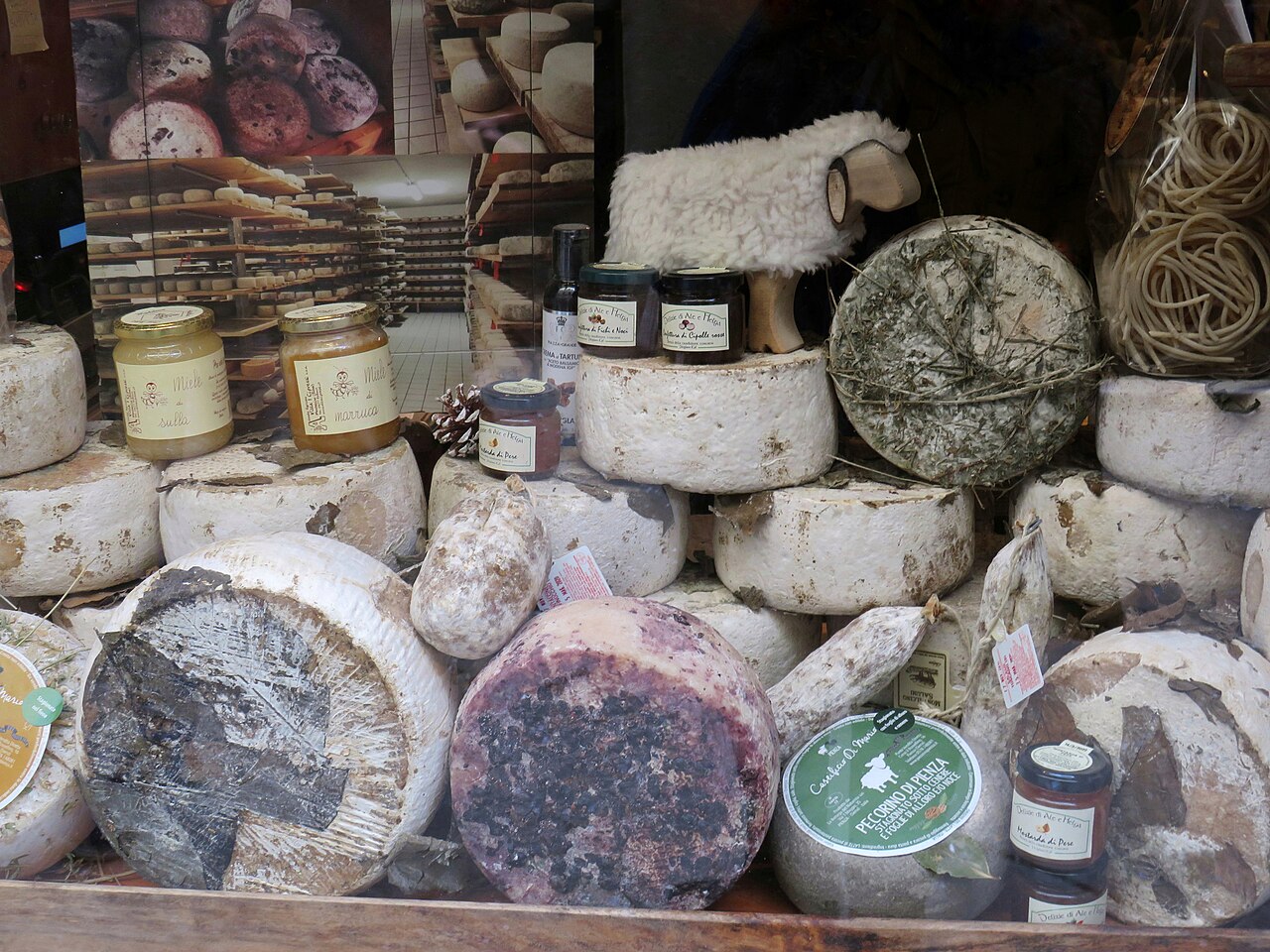 Vetrina di una bottega di Pienza con pecorini toscani affinati in foglie, cenere e vinacce